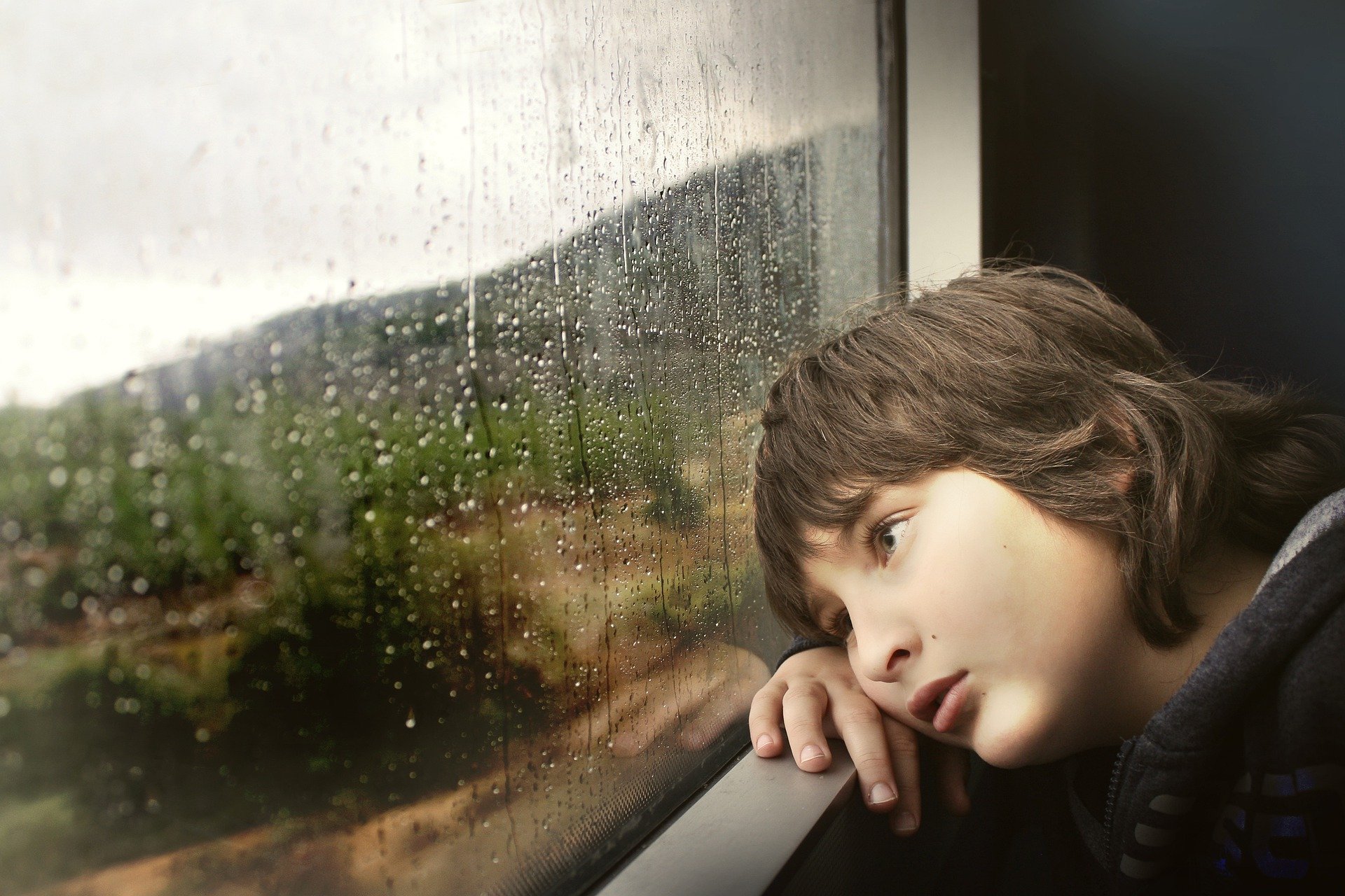Little boy sat looking out of a window