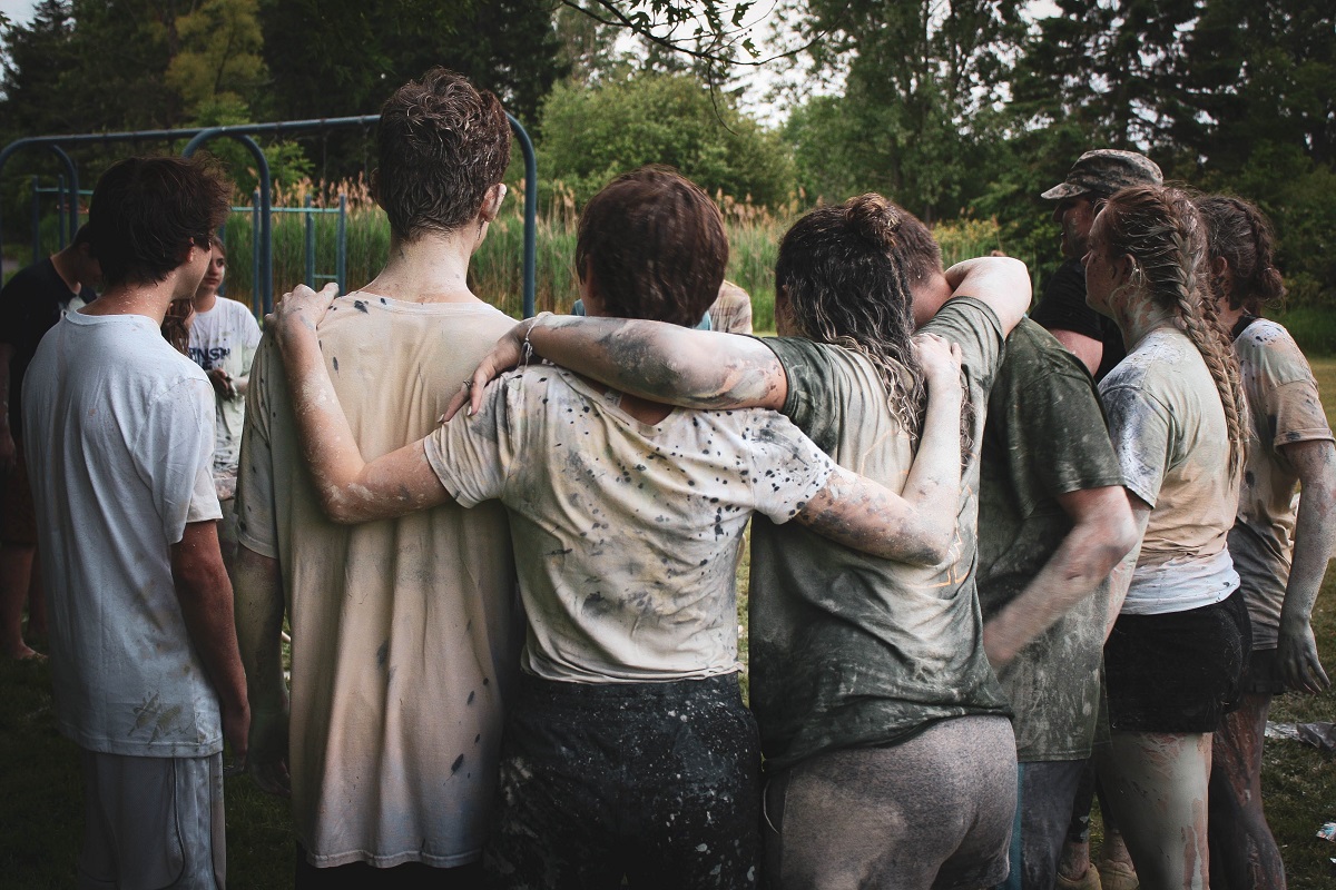 A group of muddy teenagers grouped together in a huddle