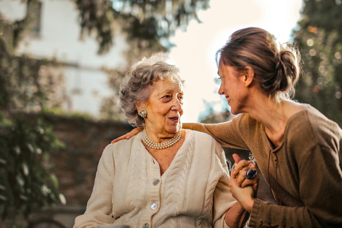 older person sat in a garden talking with a young person