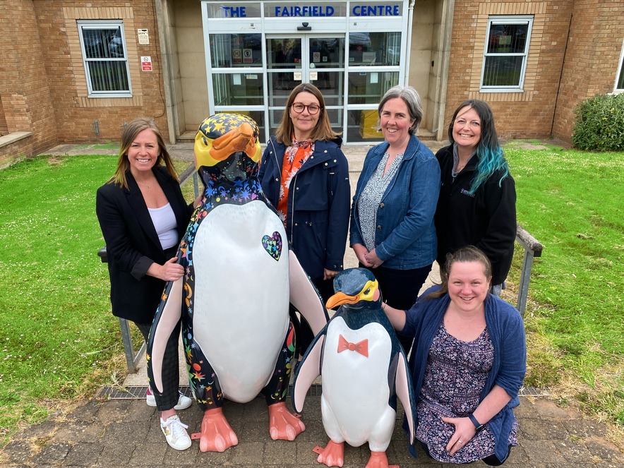 Sara Matthews from St. Richard's Hospice stands with members of Learning Services Worcestershire and two penguin statues outside the Fairfield Learning Centre in Warndon, Worcester.