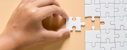 Hand inserting a jigsaw piece into a puzzle