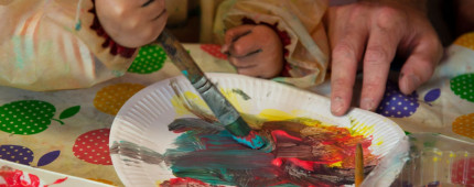 Young child using messy paint on a paper plate