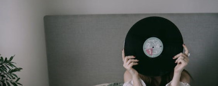 Woman holding vinyl record in front of her face