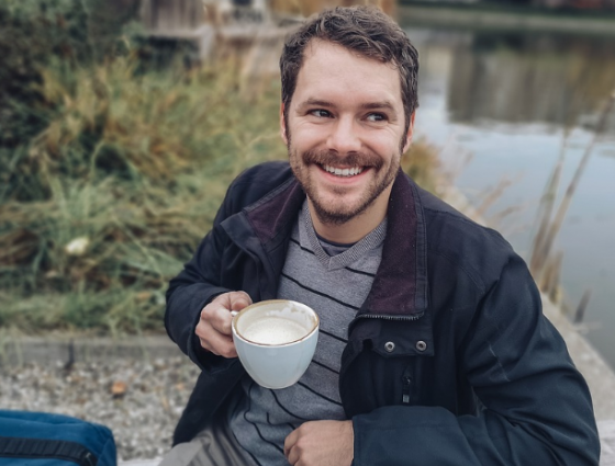 man smiling in the countryside having a coffee