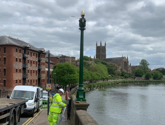 Builder in yellow high vis jacket fixing lights on the New Bridge in Worcester