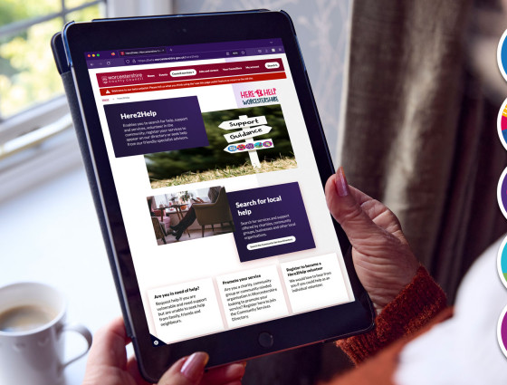 Close up of someone holding a tablet with the Here2Help webpage on the screen
