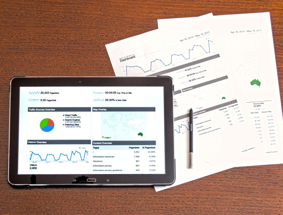 A tablet and some documents showing graphs and charts
