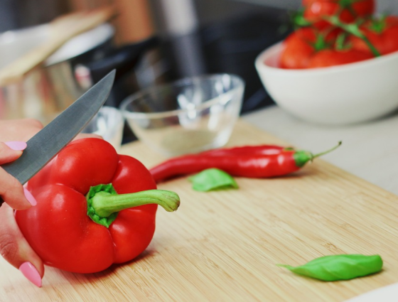 a close up of a person chopping a red pepper on a chopping board