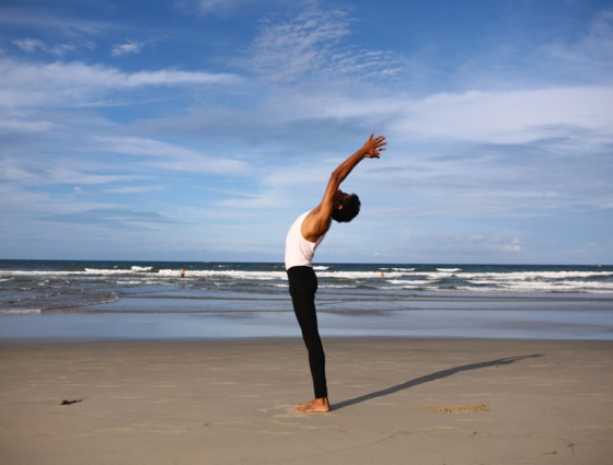 A person on a beach reaching and stretching