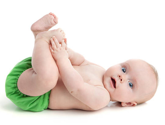 A baby wearing a green coloured reusable nappy.