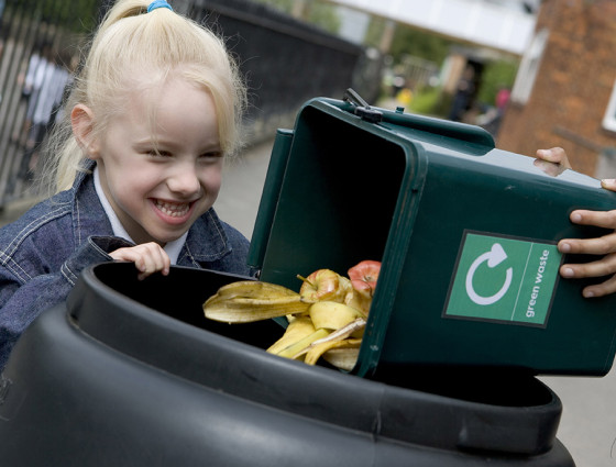 A young girl watching composting items being added to a compost bin.
