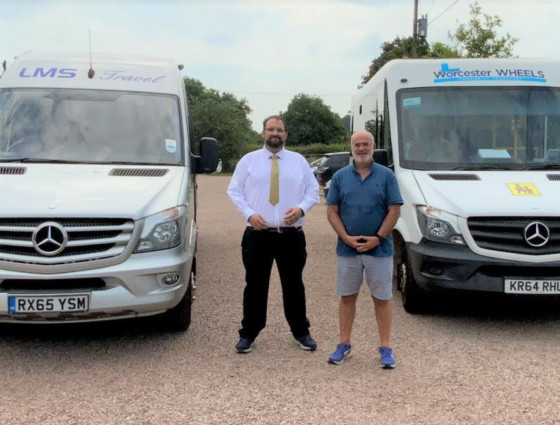 Councillors Rouse and Wells stand between two buses