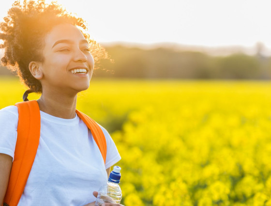 A girl in flower field with the sun behind her