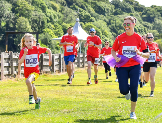 People in red t-shirts taking part in a race in a green field