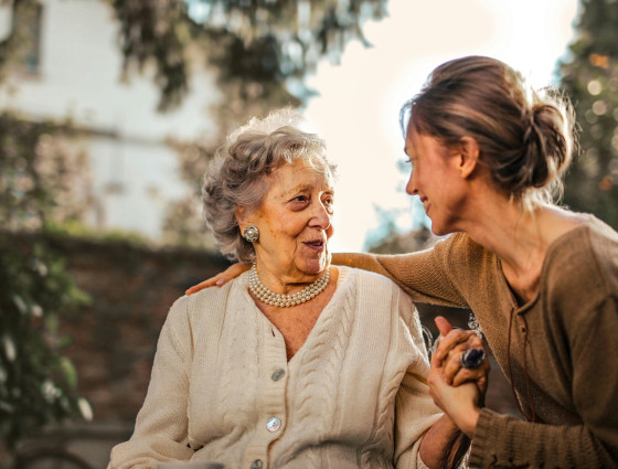 older person sat in a garden talking with a young person