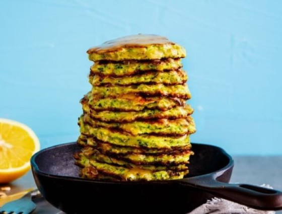 Pile of fritters in a pan with orange halve at the side