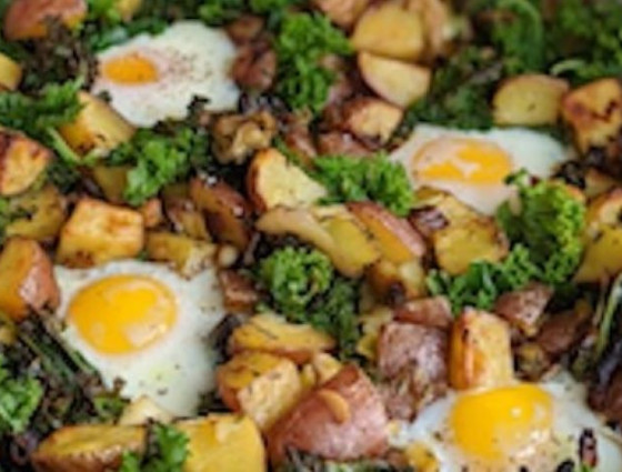 Tray with chopped up potato, kale & bacon with cooked egg on top