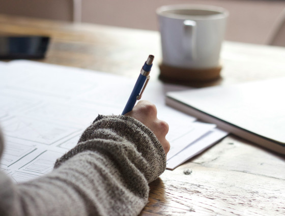 A person sat at a desk writing with a pen