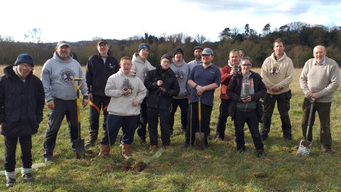 12 men planting a tree in a field