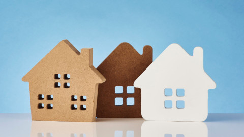 Three cork cut out houses, one beige, brown and white.