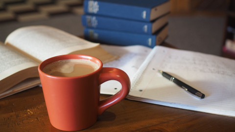 Cup of tea on a desk next to a book 