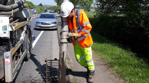 Man in high vis outfit holding a drain pipe