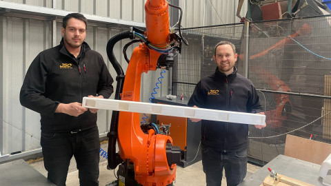 Two men holding a white plastic plank