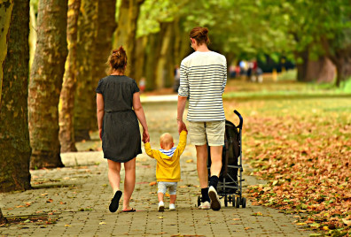 Two women walking away from the camera holding the hands of a small child