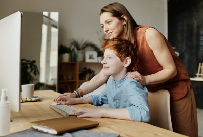 An adult helping a child to us a computer