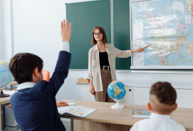 Teacher at the front of the class pointing at the whiteboard