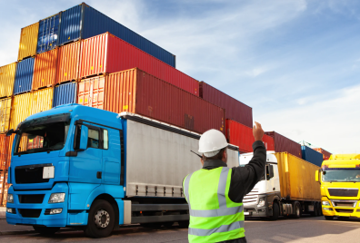 person waving a lorry through a container depot