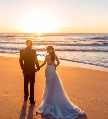 A couple standing together on a Beach in wedding attire