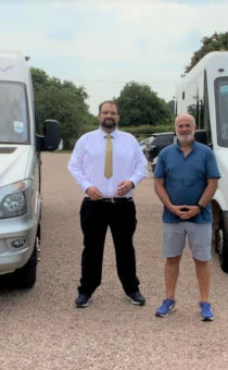 Councillors Rouse and Wells stand between two buses