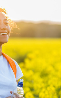 A girl in flower field with the sun behind her