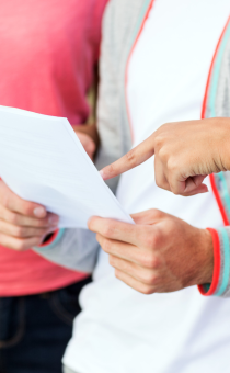 landscape image of three people pointing at an exam paper