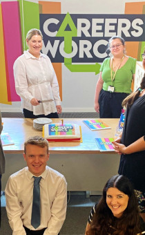 The Careers Worcs Team pose with a cake in front of the Careers Worcs banner