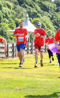 People in red t-shirts taking part in a race in a green field
