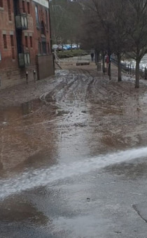 Person jet washing the road following floods